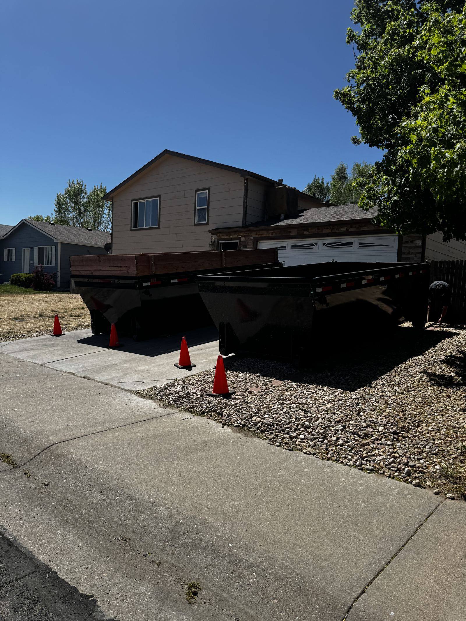 Roll-off dumpster placed in a residential driveway with safety cones