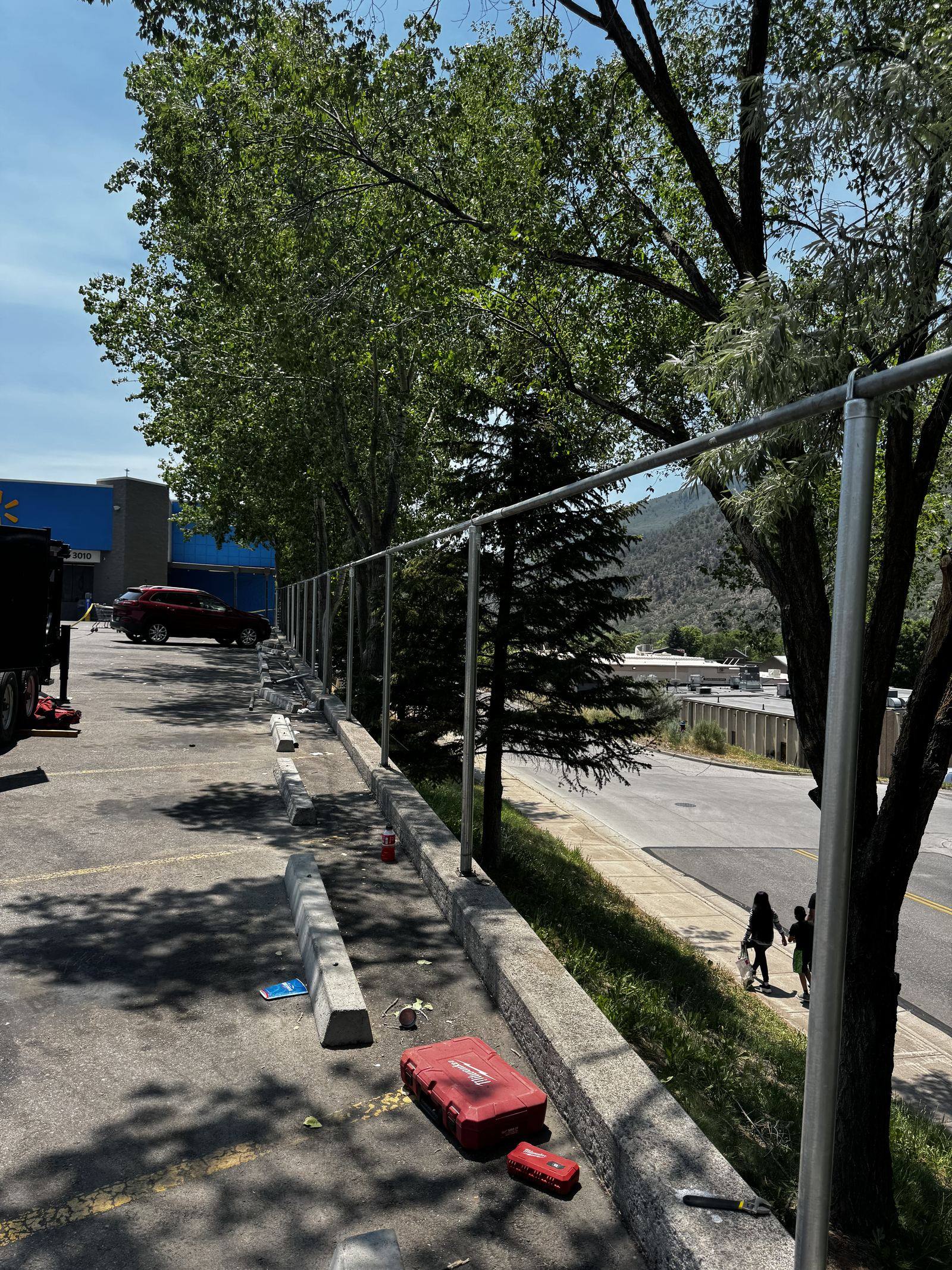 Chain-link fence framework going up along a commercial parking lot